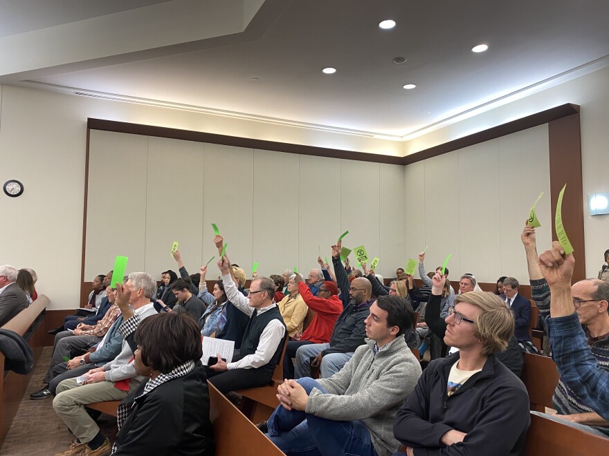 People attending the North Carolina Utilities Commission public hearing for Duke's rate increase wave green cards to agree with a speaker instead of applauding.