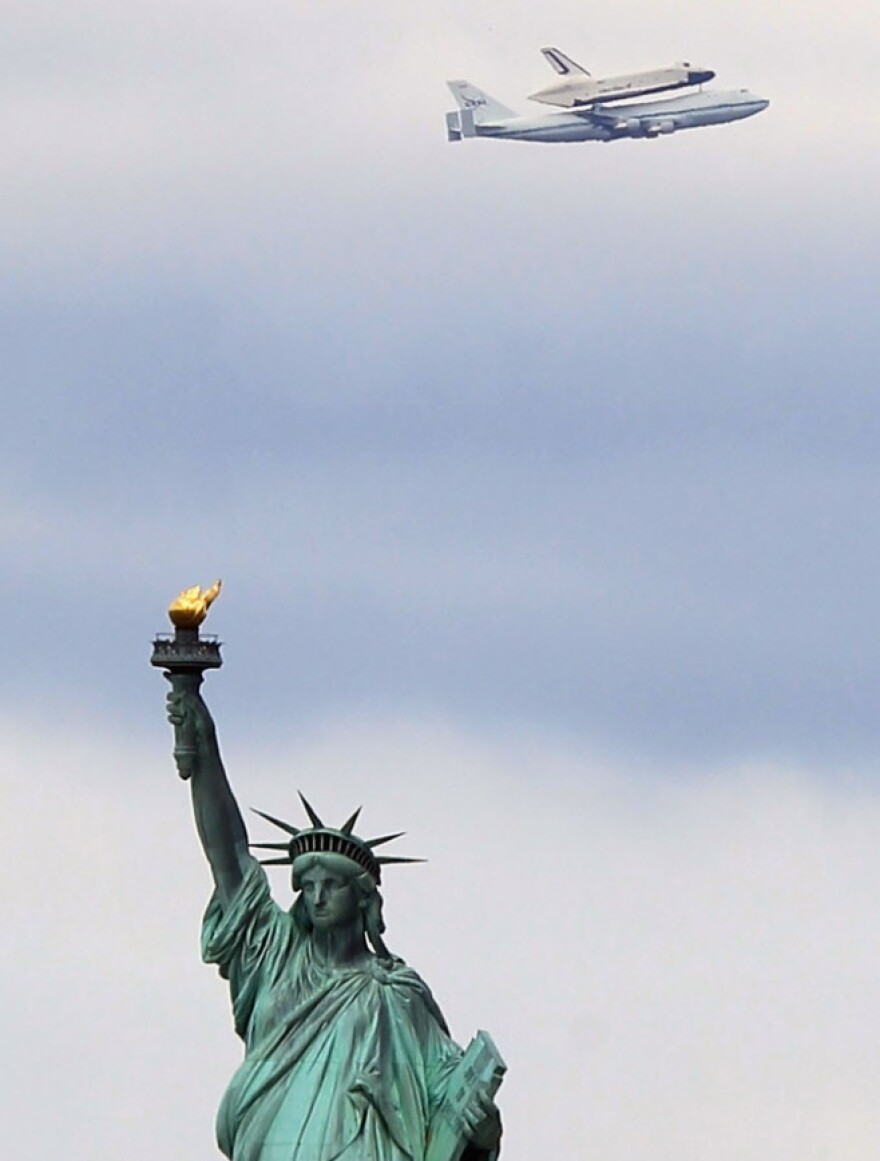 Riding atop a 747 shuttle carrier aircraft, the space shuttle Enterprise flew past the Statue of Liberty in New York Harbor today.