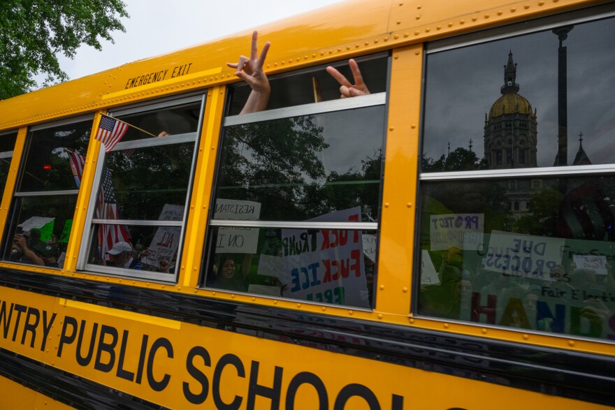 Peace signs and flags appear from the windows of a school bus passing Hartfords No Kings protest at the 窪蹋勛圖厙 State Capitol.