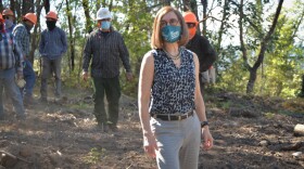 Governor Kate Brown stands in front of a crew of workers in a forest.