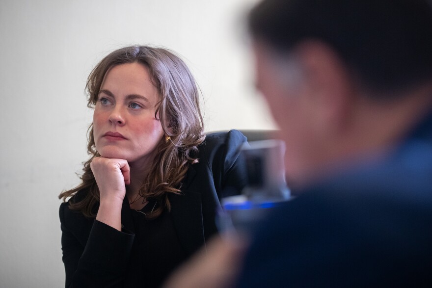A woman rests her chin on her hand while sitting at a table and looking to the side