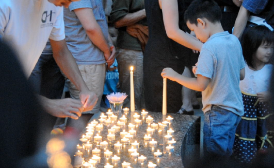 A child lays a candle around a fountain in memory of Dr. Feng Liu