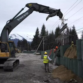 Contractors position the recovery frame over a row of HESCO barriers on Riverside Drive to help them take apart and reuse the materials.