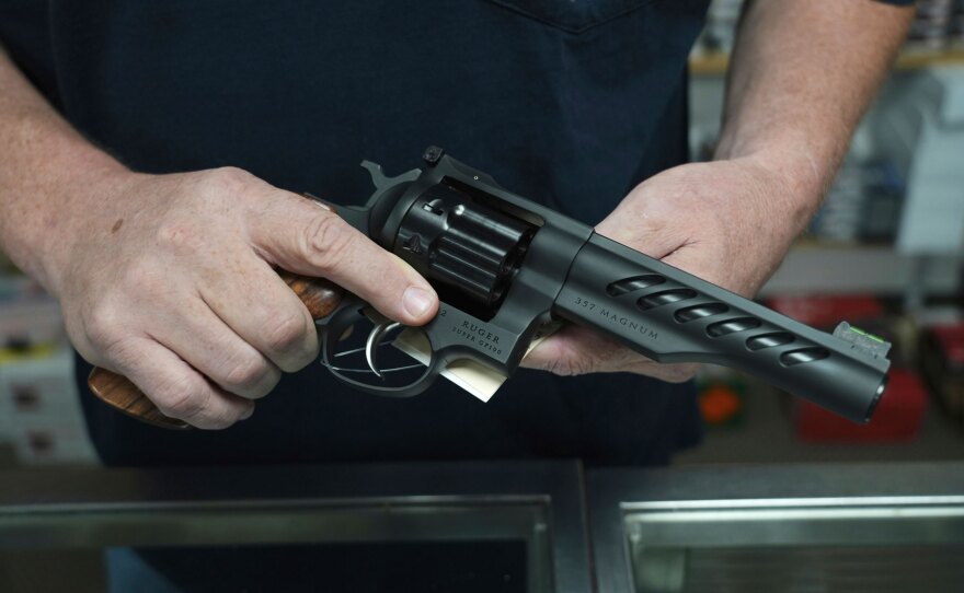 Hands holding a .357 Magnum revolver in a gun shop setting.
