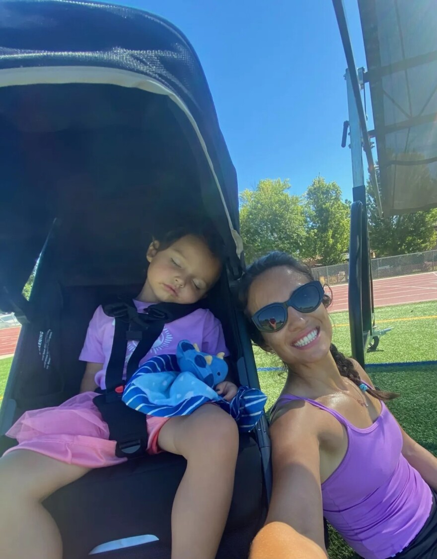 A woman in a purple tank top sits next to a child in a stroller.