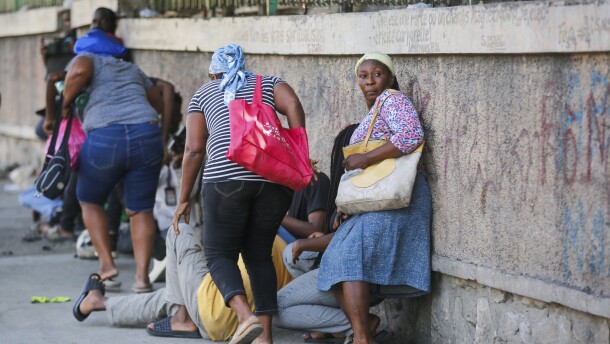 Pedestrians take cover during clashes between police and gang members in Port-au-Prince, Haiti, Friday, March 1, 2024.