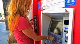 A customer uses a Bank of America ATM in Los Angeles. The bank plans to start charging a $5 monthly fee for customers who use their debit card for purchases starting early in 2012. ATM transactions would still be free.