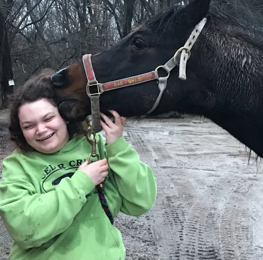 A client of Ceder Creek smiles as they are nuzzled by a horse