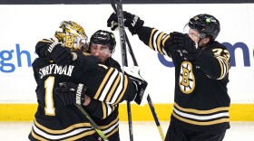 Boston Bruins goaltender Jeremy Swayman (1) is embraced by Brad Marchand as Charlie McAvoy, right, skates in for a hug following a shootout during NHL hockey game, Monday, Feb. 19, 2024, in Boston. Both Marchand and McAvoy scored in the shootout as the Bruins defeated the Stars. (AP Photo/Charles Krupa)