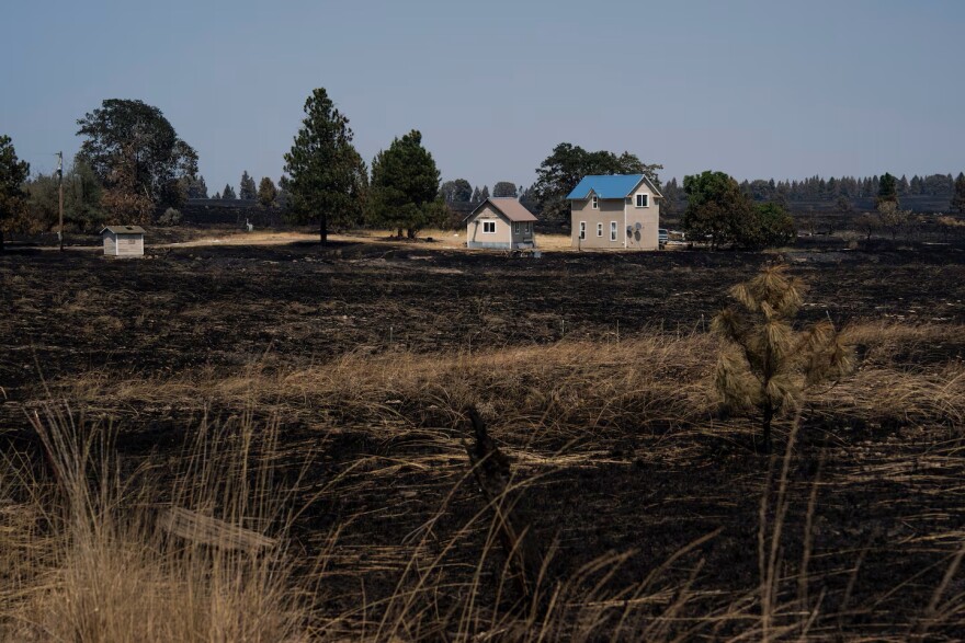 Charred vegetation surrounds a home in the unincorporated community of Friend, Ore., Aug. 13, 2026.