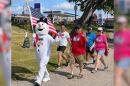 People walking on a trail with a person in a snowman costume leading the way.