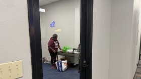 A woman in an almost empty office unpacking newspapers from a bag.