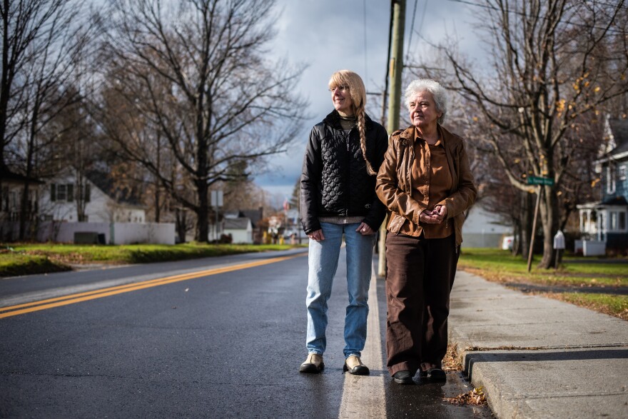 Neighbors Janice Beadle (left) and Marie Vallieres stand on their respective sides of the white stripe that marks the international border on Canusa Avenue, with the U.S. on the left and Canada on the right.