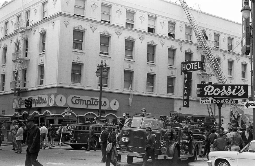 A black and white picture of Compton's Cafeteria in the 1970s with old firetrucks parked outside.