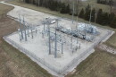 An aerial view of an electric substation. There is a square lot with steel poles and electrical boxes and wires connecting them.