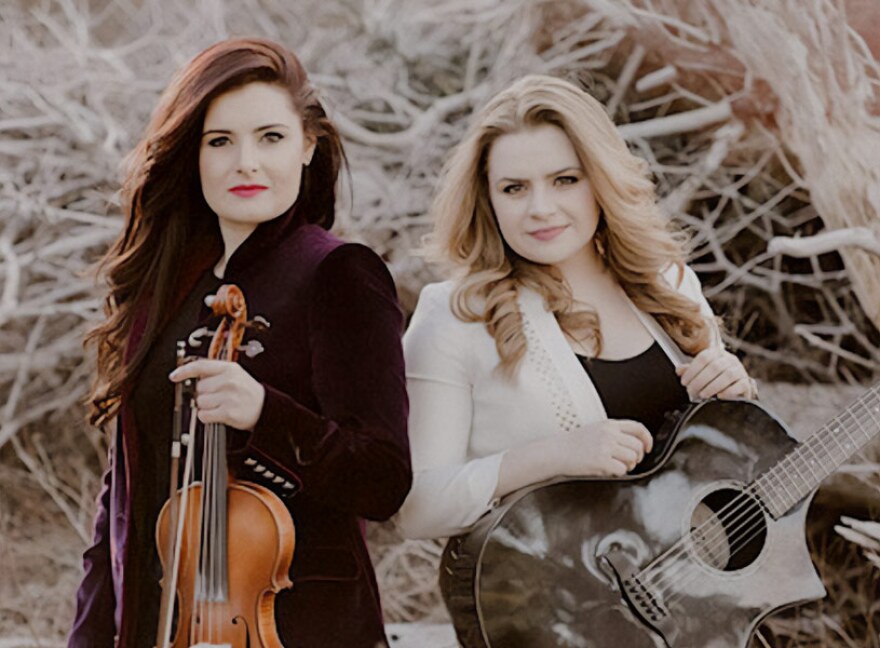 Photo of Cassie and Maggie, holding a violin and a guitar