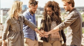 Group of happy friends holding hands as unity oath