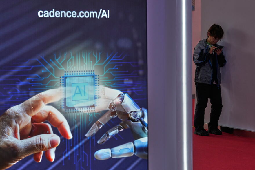 A man browses his phone near an artificial Intelligence (AI) booth at the China International Supply Chain Expo in Beijing on June 25, 2026.
