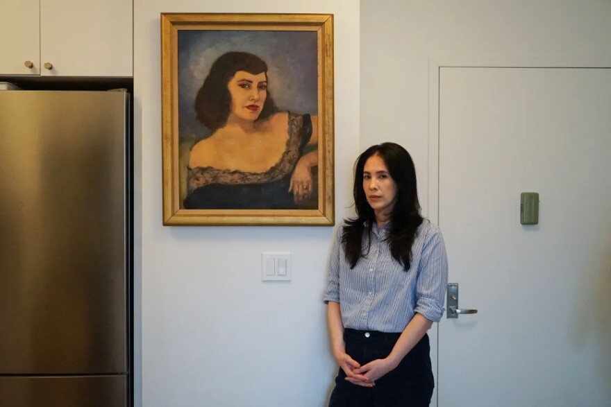 Sophia Bassan stands beside a painting of her grandmother, who died of breast cancer at 40. With a family history of breast cancer and a genetic test showing she was at risk, Bassan decided to undergo a preventive mastectomy.