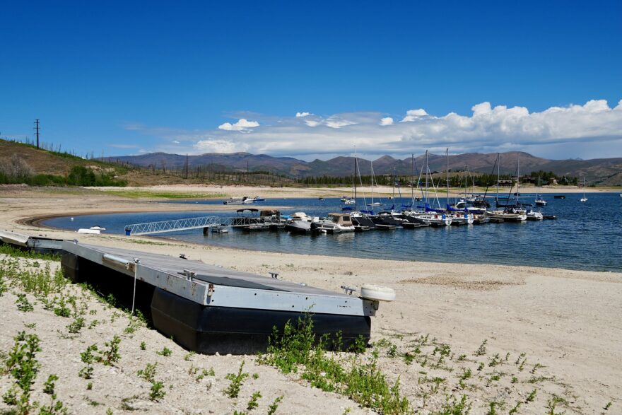 Very low water at Lake Granby shows an extended dock to get over the dirt to the boats.