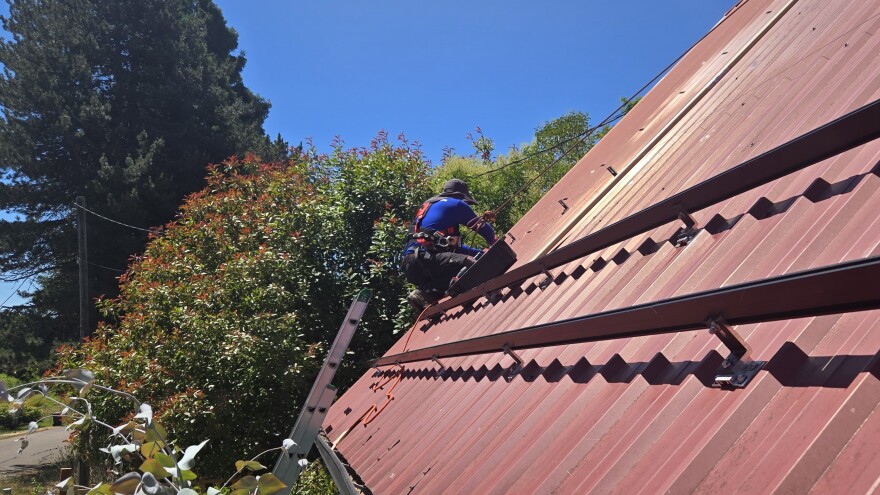 An installer with Abundant Solar adds the structural attachments to install the racks for solar panels.