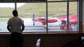 a man looks out a window at an airplane on a runway