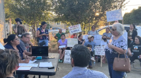 East Orosi residents hold signs in protest at an outdoor meeting.