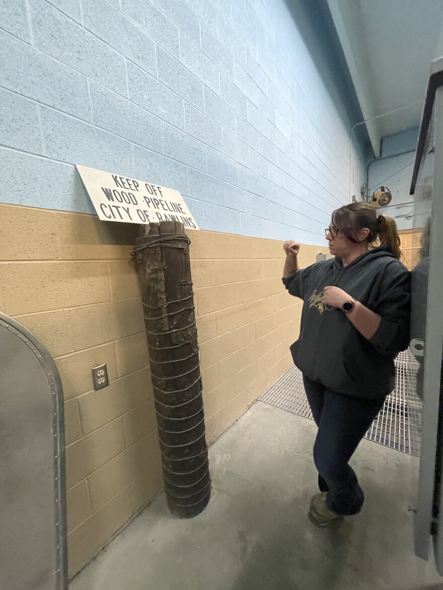 A woman stands next to the wooden pipeline that brings water to the city of Rawlins.