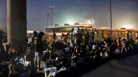 Immigrants sit near a row of portable toilets inside a migrant camp at the U.S.-Mexico border in Del Rio, Texas.