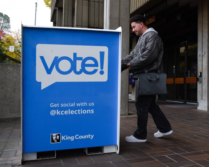 A person drops off a ballot in a ballot box. 