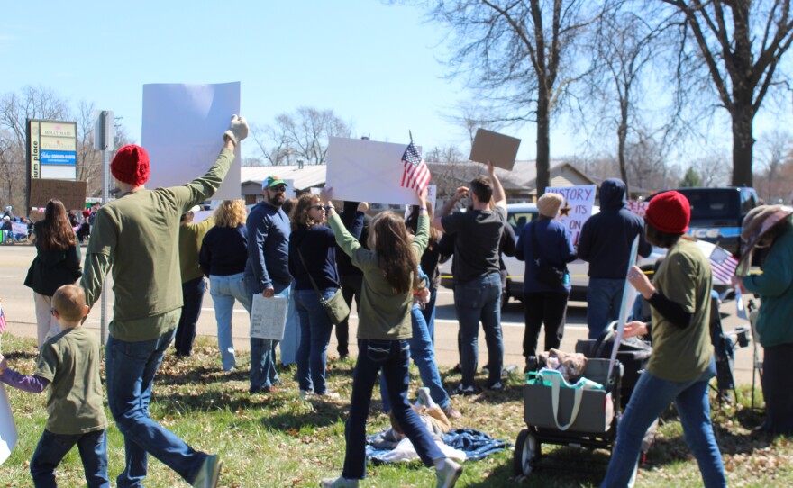 A family walks through the "No Kings" protest in peoria holding signs.