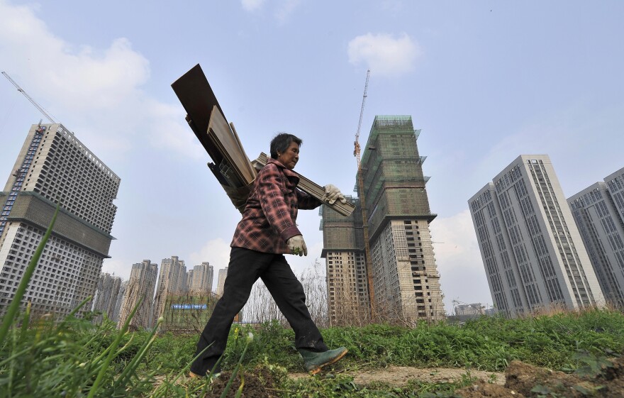 A garbage collector walks past residential and office buildings under construction in Hefei, in China's Anhui province, on April 3. China's economy has grown to the world's second-largest in the years since 1989.