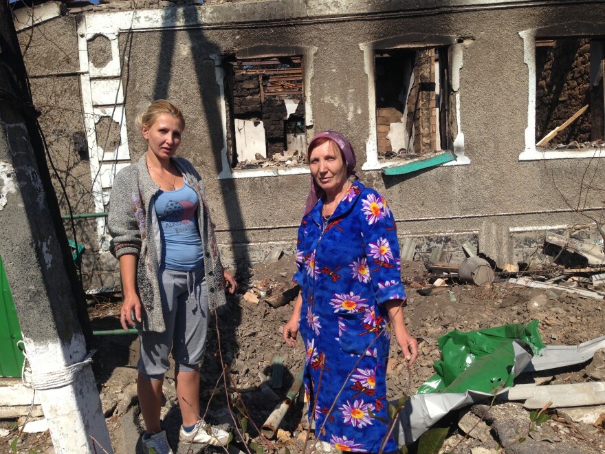 Svetlana Duginova and her daughter Klaudia Fedorashko pick through the rubble of Duginova's parents' house in the shelled village of Novokaterinovka. "We are all so tired of this," they say.
