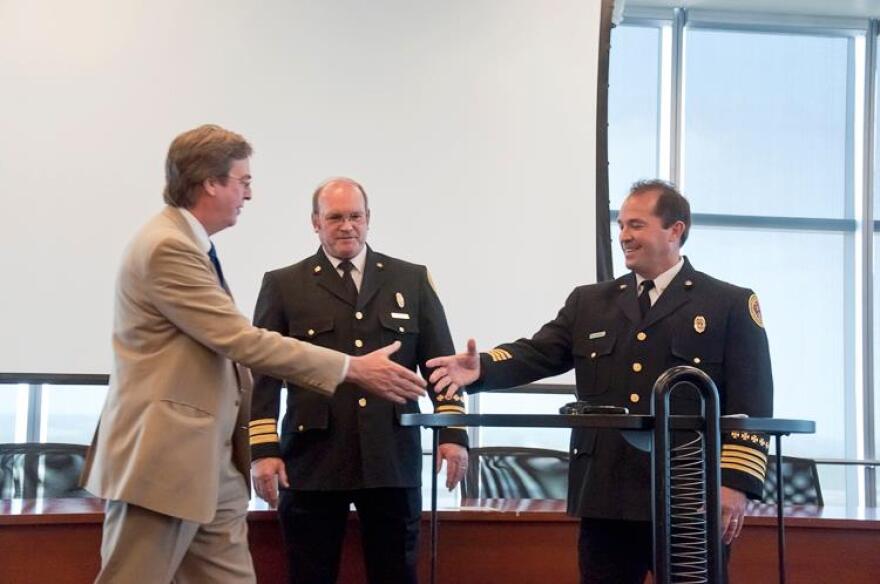 Mayor Bartlett shakes hands with new Fire Chief Ray Driskell as retiring Chief LaCroix watches