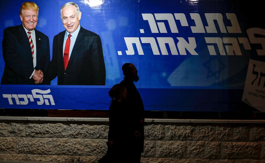 Pedestrians pass an Israeli election billboard for Prime Minister Benjamin Netanyahu's Likud Party, which depicts him shaking hands with President Trump. The caption written in Hebrew reads: "Netanyahu, in another league."