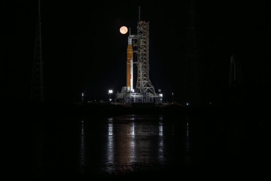 The full Moon is seen behind NASA’s Artemis II Space Launch System (SLS) rocket and Orion spacecraft, standing atop a mobile launcher at Launch Complex 39B, Sunday, Feb. 1, 2026, at NASA’s Kennedy Space Center in Florida. 