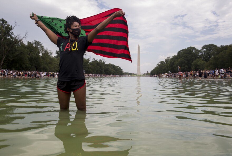 Poetry Pool of Baltimore, MD, holds a flag as she stands in the reflecting pool. She walked to Washington, D.C. from Baltimore with 10 people from her organization A.A.D. It took them 2 days.