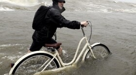 Tyler Holland guides his bike through the water as winds from Tropical Storm Barry push water from Lake Pontchartrain over the seawall Saturday.