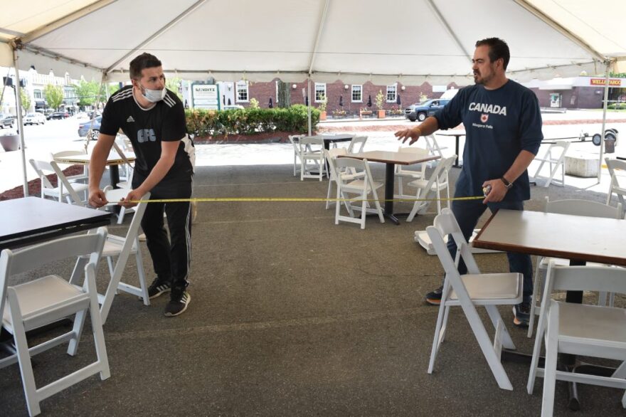 Last summer, Sammy Bajraktarevic (right), owner of Luce Restaurant in Middletown, and server Alex Cirikovic set up socially distanced tables for a dining area in the restaurant’s parking lot as part of reopening amid the pandemic..