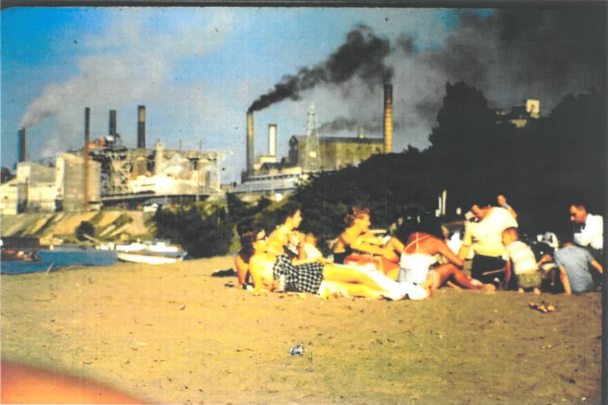 Archived photo of a group of beach goers at Fairport Harbor Lakefront Park with the Diamond Shamrock Chemical Plant operating in the background. 