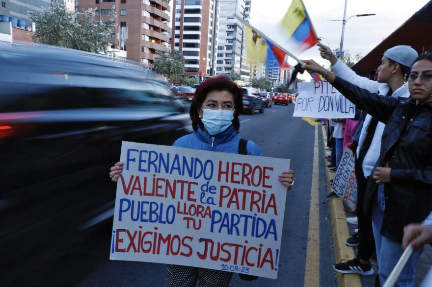 Following Villavicencio's assassination, a woman holds a sign reading: "Fernando, valiant hero of the motherland, the village weeps for your parting, and we demand justice!"