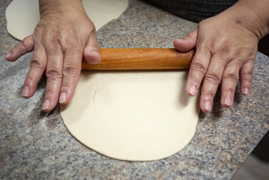 Josie Vera rolls out dough to make a tortilla.