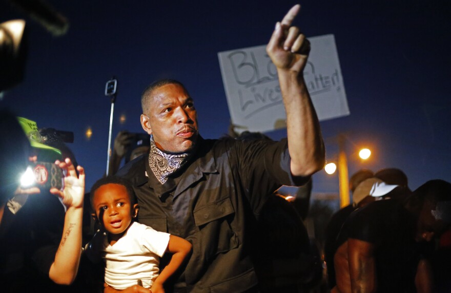 A father holds his son as he takes part in a demonstration in Ferguson, Mo., on Monday night. Police arrested more than 20 people in the city's streets Monday night; no violence or damage was reported.