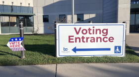 A big white sign with a red arrow and letters reads: "Voting Entrance."