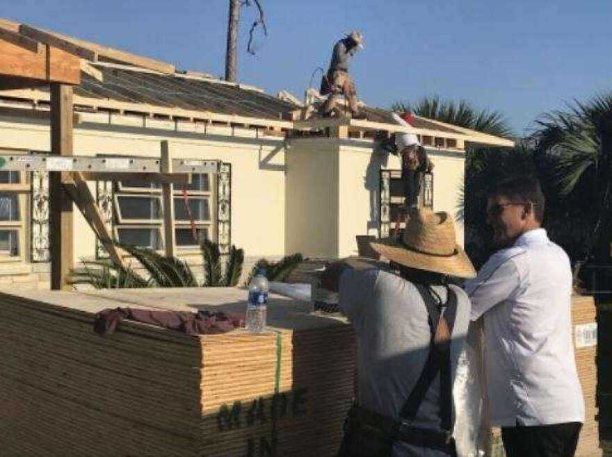 Contractors replace a roof on a Panama City resident's home almost one year after Hurricane Michael devastated the region. (Valerie Crowder/WFSU)