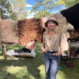 A rtist Kelly Moody at the Mountain Harvest Festival standing in front of hides tanned.