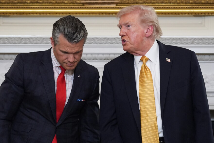 FILE - President Donald Trump talks with Defense Secretary Pete Hegseth after a roundtable on criminal cartels in the State Dining Room of the White House, Oct. 23, 2025, in Washington.