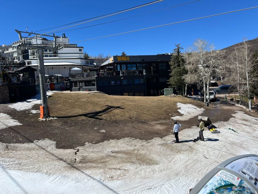 A skier and snowboarder observe a patch of dirt on the Fanny Hill run near the Snowmass Village Mall on Saturday, March 21, 2026.
