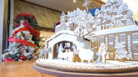 A gingerbread display on a table next to a Christmas tree