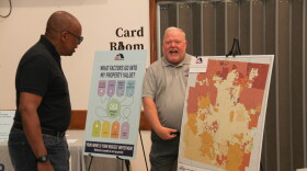  A man points to a coded map while another man looks on. 